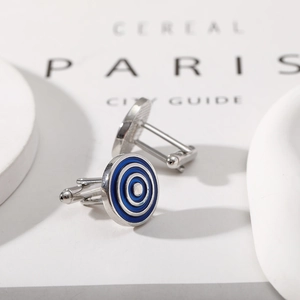 Macro view of silver cufflinks with blue concentric rings on a modern white background