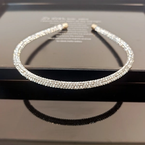 Detailed view of silver rhinestones headband with golden tips on a black reflection surface