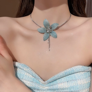 Detail of blue glitter fabric flower pendant with metallic tassels on a snake chain