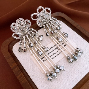 Detailed macro shot of silver bead fringe earrings on a luxury display wooden tray