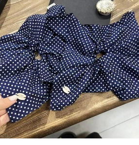 Detailed view of navy blue polka dot scrunchies with decorative white shell charms