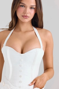 Vue détaillée du corset licou blanc avec rangée de boutons et détails froncés sur le côté