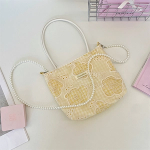 Détail d'un sac à carreaux jaunes avec dentelle rose et bandoulière en perles fines