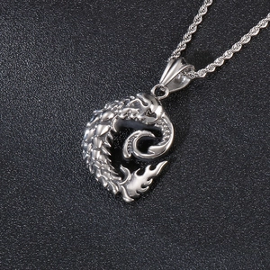 Macro shot of silver dragon totem pendant with detailed scales on twisted metal chain