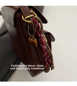 Detail of brown faux leather crossbody bag featuring gold metal rings and a woven charm