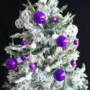 Albero di Natale decorato con ornamenti viola e bianchi di varie dimensioni e trame
