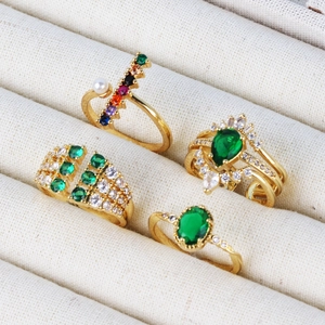 Detail of four gold-plated rings with colorful zircons and pearls in a jewelry box