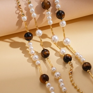 Close-up of elegant long necklace with white faux pearls and tiger eye stones