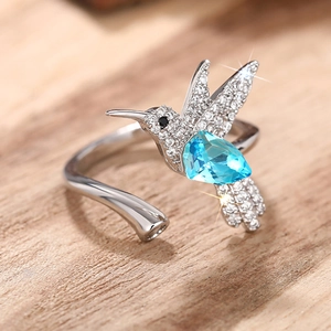 Detailopname van kolibrie ring met blauwe druppelvormige edelsteen op hout