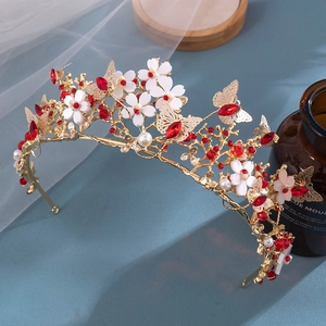Detail of golden Baroque crown with white flowers, red rhinestones and butterfly accents