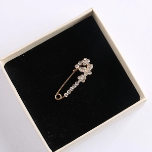 Macro detail of golden butterfly flower brooch with crystals in beige gift box