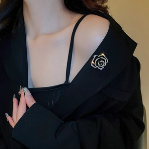 Détail d'une broche camélia en zircon avec pétales noirs sur revers de blazer