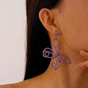 Close-up of a large purple rhinestone butterfly drop earring on a female model