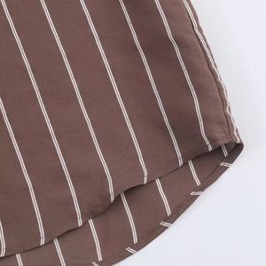 Detail of vertical stripes and fine curved hem stitching on brown woven shirt fabric