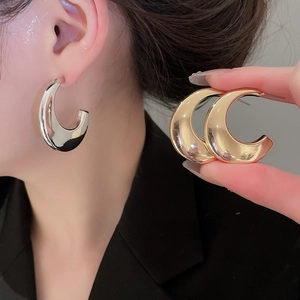 Macro detail of glossy metallic C-shaped stud earrings in silver and gold finishes