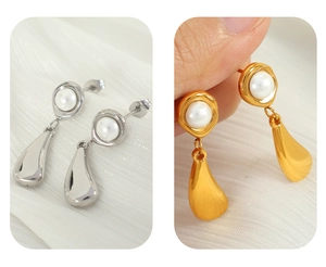 Close-up of gold and silver plated metal teardrop earrings with white pearl accents