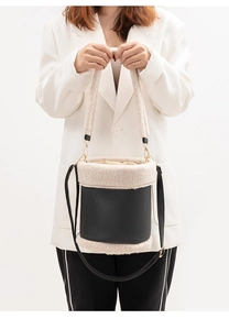 Detail of black and white plush bucket bag showing faux fur texture and long strap