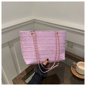 Detail shot of the pink textured checkered fabric and gold interwoven chain strap on the bag