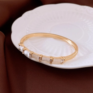 Détail d'un bracelet doré avec pierre œil de chat et zircons sur fond en soie élégant