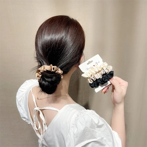 Elegant satin hair scrunchies set in champagne and white on a stylish low bun