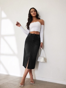 Detail van de voorspleet van een zwarte denim midi-rok met hoge taille en witte top