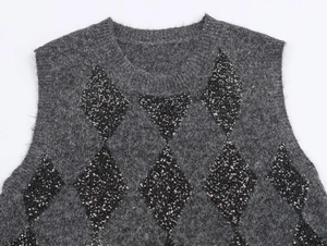 Detail view of grey knitted vest with black sequin diamond patterns and fuzzy texture
