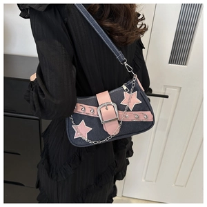 Detail of Y2K denim underarm bag with pink star patches and metallic chain decorations
