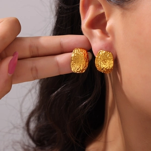 Boucles d'oreilles rectangulaires dorées avec texture martelée portées par un mannequin
