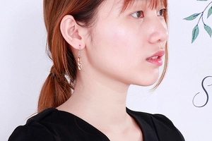 Detail of rose gold chain link earrings on model with sleek metallic finish