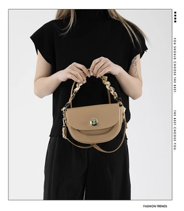 Close-up of saddle bag with silk scarf wrapped handle and gold round twist lock detail