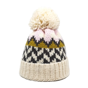 Detailed view of winter knit beanie with colorful jacquard patterns and a fluffy pom-pom