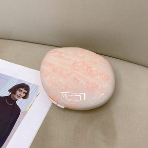 Top view of pink marble pattern oval clutch bag on a soft beige leather surface