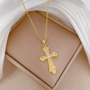 Elegant gold titanium steel cross necklace with zircon pavé on white silk background