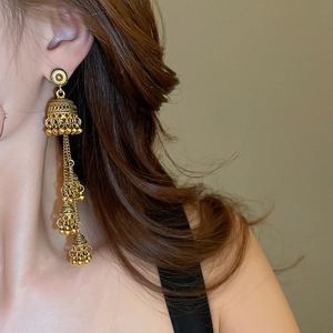 Detail of vintage gold layered Jhumka earrings with geometric tassels on model