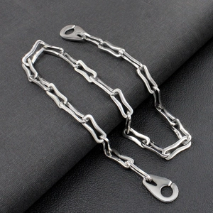 Macro shot of silver metal chain with flat boomerang links on a dark textured surface