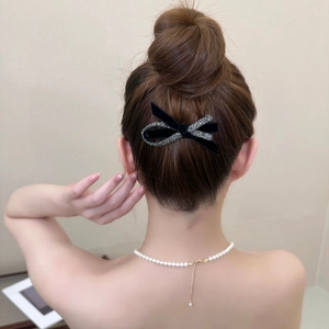 Detail of elegant black bow hair clip with sparkling rhinestones on model bun hairstyle