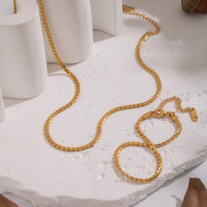 Minimalist golden stainless steel box chain necklace and bracelet set on white stone