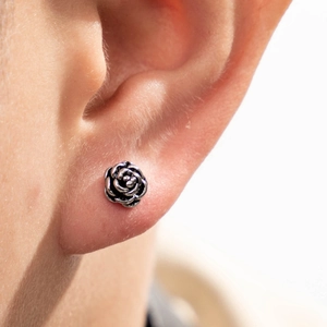 Silver stainless steel rose stud earring worn on ear showing detailed floral casting