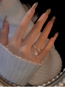 Close-up of gold bow ring with sparkling zircons and hanging pearl tassels on a finger
