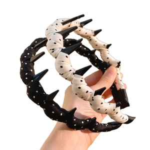 Chic white polka dot headband with unique black wave spikes for a trendy feminine hair look