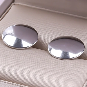 Macro shot of silver oval earrings with mirror finish in a beige jewelry box