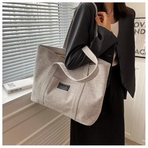 Close-up of grey canvas tote bag showing the high-quality fabric texture and fashion label