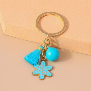 Detail of blue tassel bell and snowflake charm on gold Christmas keychain accessory