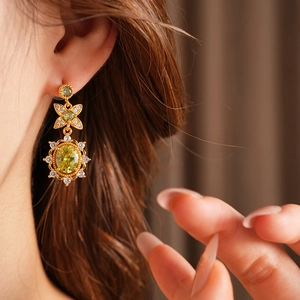 Détail de boucles d'oreilles vintage en or avec gemme verte ovale et zircons sur modèle