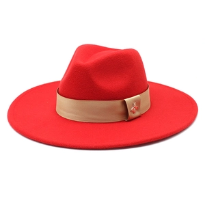 Detail of red wool felt hat featuring champagne ribbon and golden bee metal emblem