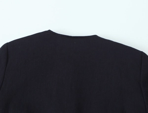 Close-up detail of dark twill fabric and neckline of the gold button blazer suit