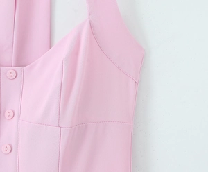 Dettaglio macro dell'abito rosa con bottoni in resina coordinati e trama del tessuto