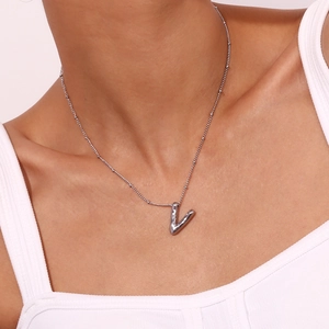 Detailed view of silver letter V pendant on bead chain worn by a female model