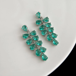 Détail de boucles d'oreilles fleur en argent avec pierres vertes sur une assiette