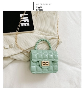 Detail of light green quilted jelly bag with golden turn-lock and chain strap on fabric